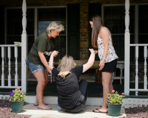 Rebecca Droke/Post-Gazette--Tuesday, June 21, 2016-- STORY BY KATE GIAMMARISE--Sandy Etling, left, and habilitation aid Stacy Yvanek, right, have to jointly hoist Abbey from the walkway onto the porch outside the Etling's home in Latrobe on Tuesday, June 21, 2016. Abbey now struggles to navigate steps and other changes in walking surfaces after losing the daily services she got as child with an intellectual disability and autism.